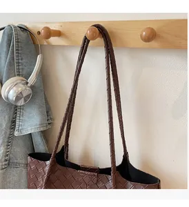 Detail of woven faux leather tote bag with thick braided handle on wooden hanger