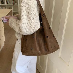 Brown suede tote bag with hollow flower patterns shown in a lifestyle setting