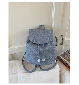 Close-up of blue tweed backpack featuring woven texture and elegant white pearl drawstring