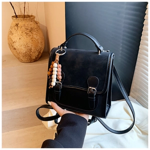 Detail of vintage black crossbody bag with matte texture and ethnic tassel charm