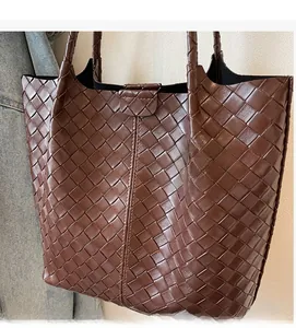 Detail of dark brown woven leather texture on a large capacity tote bag with dual straps