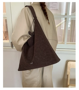 Detailed back view of a large dark brown triangular bucket bag on a model in a beige trench coat