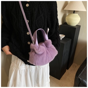 Détail d'un sac seau en fausse fourrure violette avec poignée et bandoulière sur un mannequin