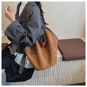 Detail of a brown matte suede tote bag with a minimalist slouchy bucket silhouette
