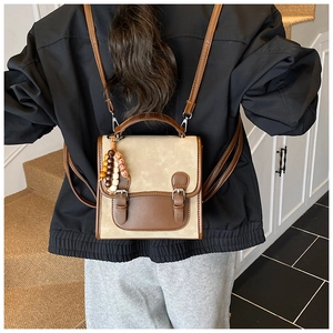 Detail of vintage faux leather backpack with contrast trim and wooden bead pendant accessory