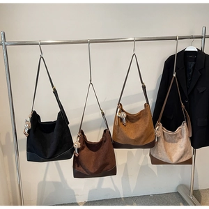 Detail of four large suede bucket bags in different colors with cute bear charms