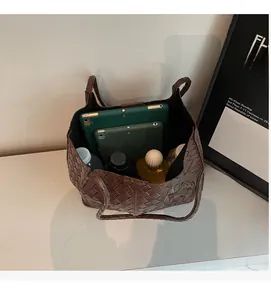 Top view of spacious brown woven tote bag interior holding a tablet and daily items