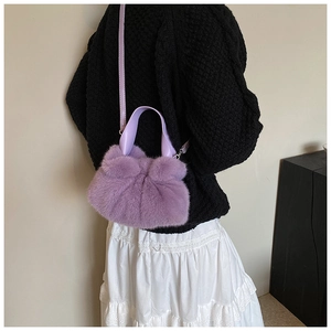 Détail du sac seau en fausse fourrure violette avec nœud pelucheux et anse en cuir