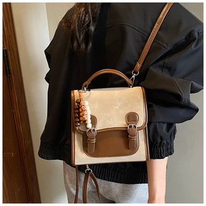 Detail of retro patchwork crossbody bag with decorative strap buckle and beaded charm