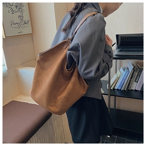 Detail of tan suede tote bag with laptop and books in a modern home office setting
