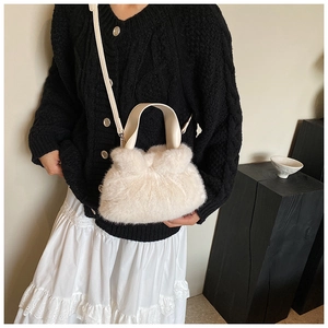 Vue détaillée du sac seau en peluche blanche porté avec une tenue chic noir et blanc