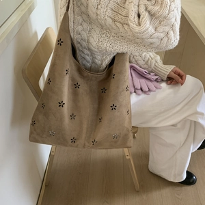 Detail of camel suede tote bag with laser-cut floral patterns and slouchy winter styling