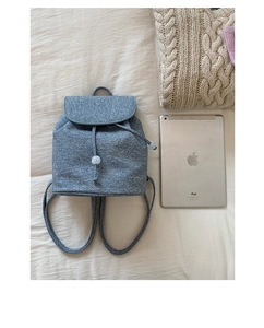 Detail of light blue textured backpack with drawstring closure and white beads decor