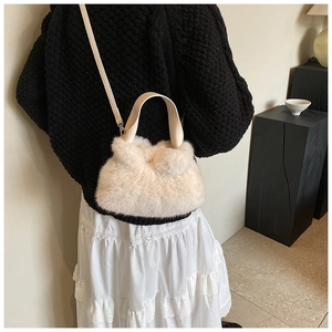 Détail du sac seau en fausse fourrure crème avec poignée en cuir et bandoulière réglable