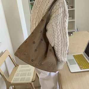 Brown suede tote bag with laser-cut floral patterns shown in a cozy lifestyle setting