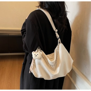 Détail du sac en cuir crème avec chaîne argentée et porte-clés ours en peluche
