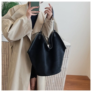 Close-up of large black matte suede tote bag with slim straps worn with a beige trench coat