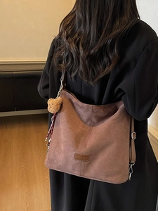 Braune große Hobo-Tasche aus Wildleder mit Bärenanhänger und Schultergurt am Model