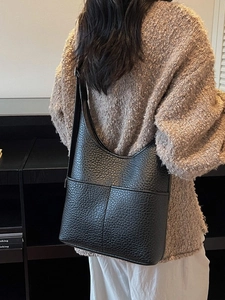 Minimalist black pebble grain leather hobo bag with wide shoulder strap on casual outfit