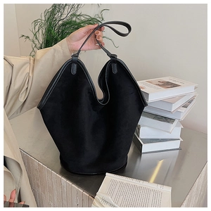 Detail of minimalist black matte suede tote bag with leather piping in home setting