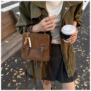 Detailed shot of a vintage brown crossbody bag featuring suede texture and wooden beads
