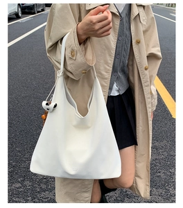 Detailed view of cream leather tote bag with decorative black and white charm accessory