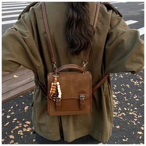 Detail of brown vintage flap backpack with parallel metal buckles and beaded tassel