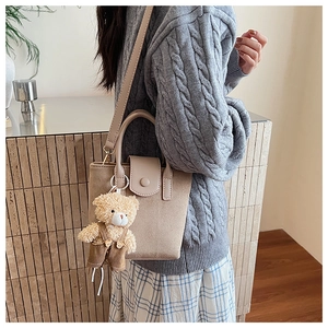 Detail of apricot matte tote bag with shoulder strap and a cute plush bear pendant