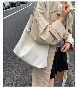 Detail of cream-white large leather tote bag with subtle Oxford London text on street