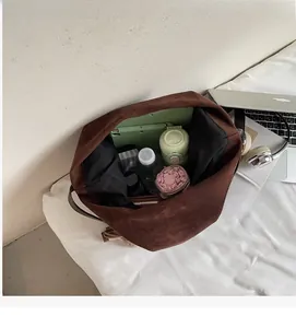 Macro detail of spacious brown suede bucket bag interior showing tablet and water bottle