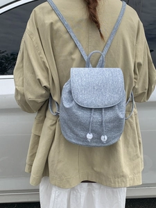 Minimalist grey bucket backpack with drawstring and pearl detail on female model