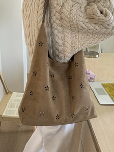 Brown faux suede hobo tote bag with floral cutout detail worn by model in casual setting