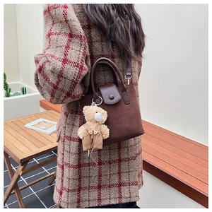 Detail of vintage matte brown bucket bag worn with a stylish red plaid winter coat