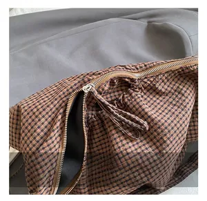 Detailed close-up of premium silver metal zipper on the plaid crescent shoulder bag
