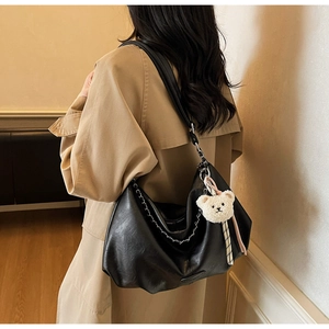 Détail d'un grand sac hobo noir avec chaîne métallique et pendentif ours en peluche blanc