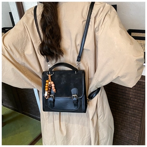 Rear view of vintage black faux leather backpack with decorative beaded pendant charm