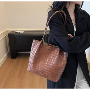 Detailed view of caramel brown woven leather tote bag with long shoulder straps