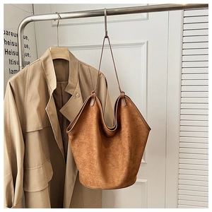 Detail of deep brown frosted leather tote bag with subtle matte texture and thin strap