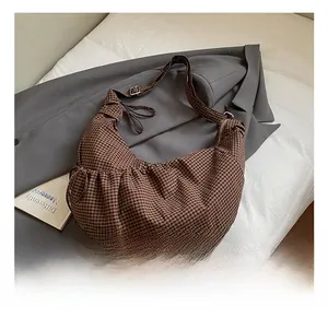 Macro detail of brown checkered moon bag with metal zipper and adjustable strap
