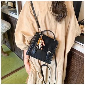 Detail of vintage black crossbody bag with double buckle closure and colorful bead charm