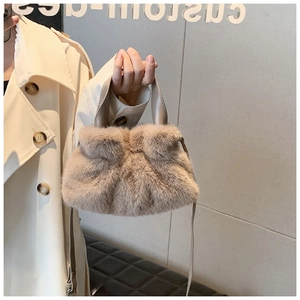 Détail d'un sac seau en peluche kaki porté par un mannequin en trench-coat beige