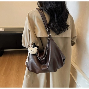 Vue détaillée du sac cabas marron vintage avec chaîne argentée et breloque ours