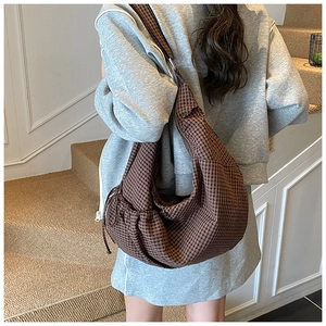 Detailed view of a brown checkered hobo bag worn by a model in a casual setting