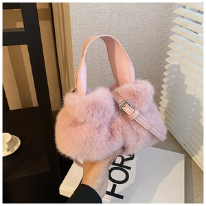 Vue détaillée du sac seau en fausse fourrure rose avec poignée en cuir et décor