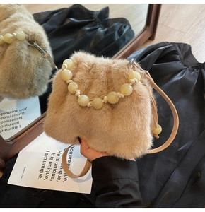 Nahaufnahme der beigen Kunstpelz-Handtasche mit gelbem Perlengriff und Leder-Schultergurt