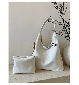 Close-up of a white leather hobo tote bag and small zipper pouch with bead charm detail