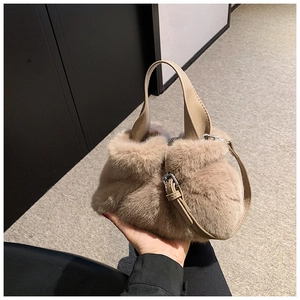 Gros plan détaillé du sac seau en peluche beige avec poignées en cuir et fermoir argenté