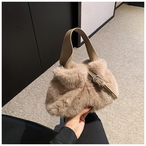 Gros plan sur la texture en fausse fourrure avec bride en cuir et boucle argentée du sac