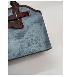 Detail of blue denim fabric with dark brown leather trim and silver metal buckle