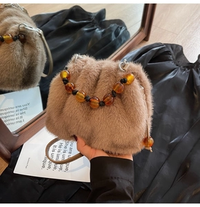Detail der Pelz-Eimertasche mit Bernstein-Perlengriff und Lederriemen in Spiegelreflexion